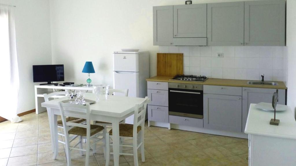 a kitchen with white cabinets and a white table and chairs at Sa Tirìa in Chia