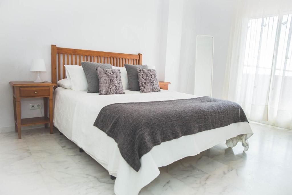 a white bedroom with a large white bed with pillows at Apartamento Las Chapas - bonito y tranquilo in Marbella