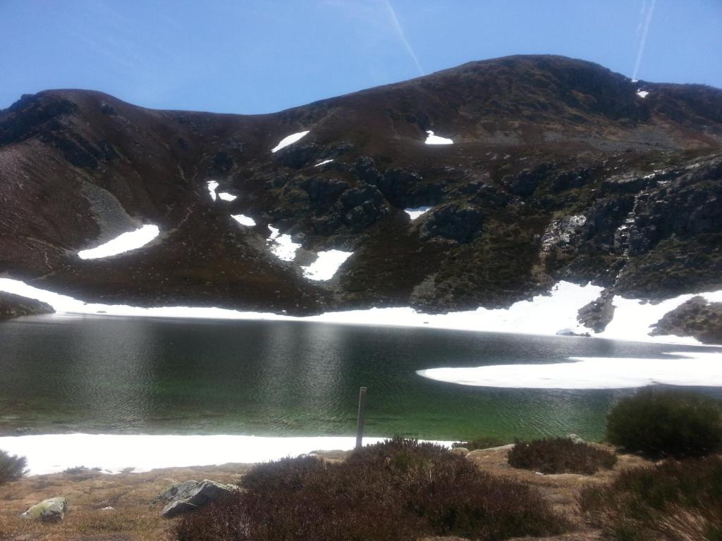 una montaña con nieve y un cuerpo de agua en Apartamento rural Felechosa, en Felechosa