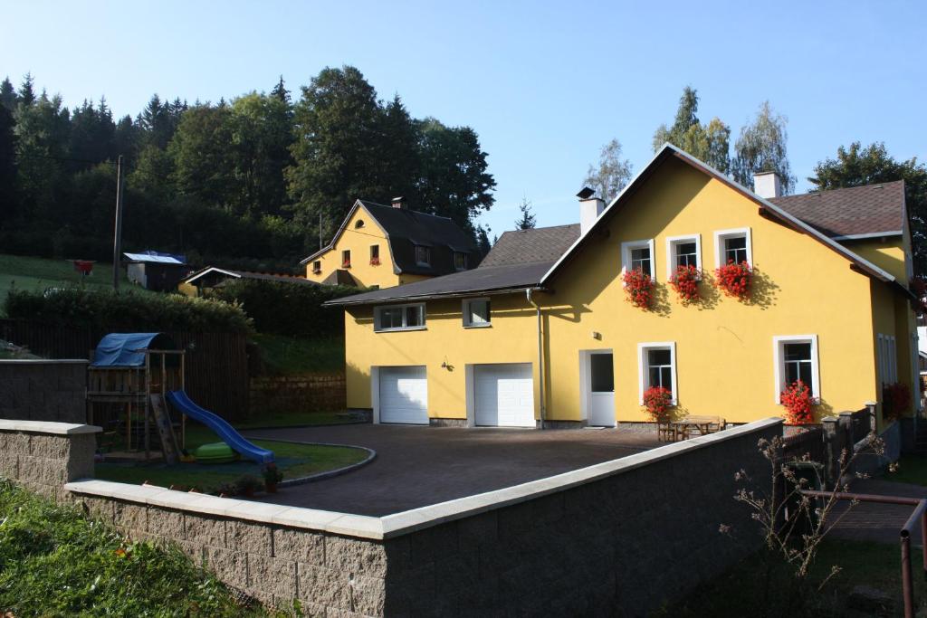 una casa amarilla con parque infantil en el patio en Apartmány Doma en Janov nad Nisou