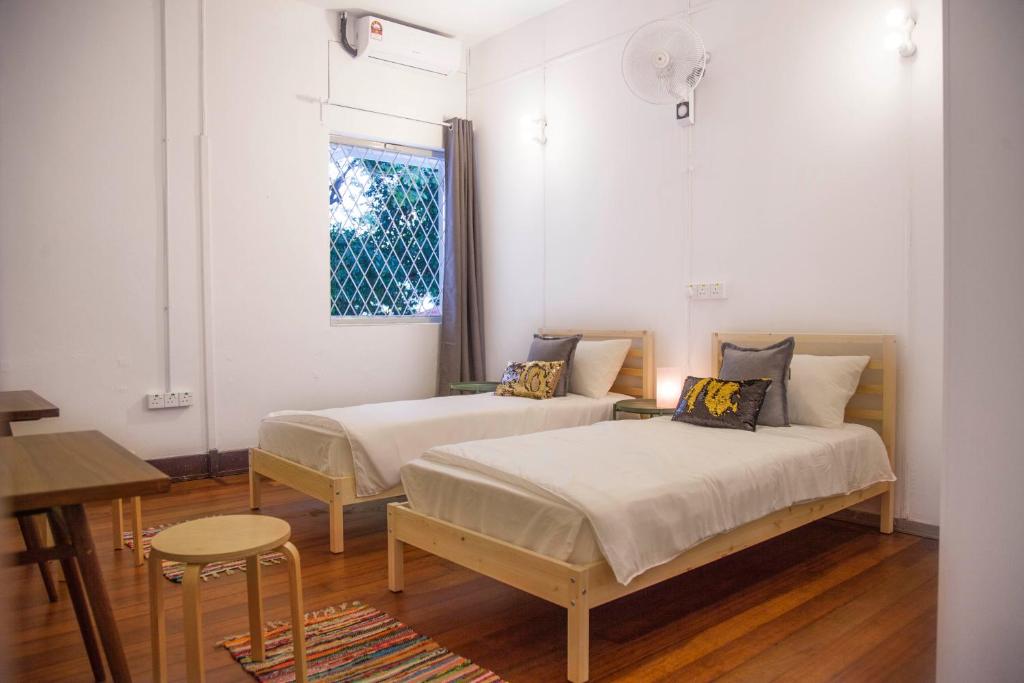 a bedroom with two beds and a table and a window at YWCA Kuala Lumpur in Kuala Lumpur