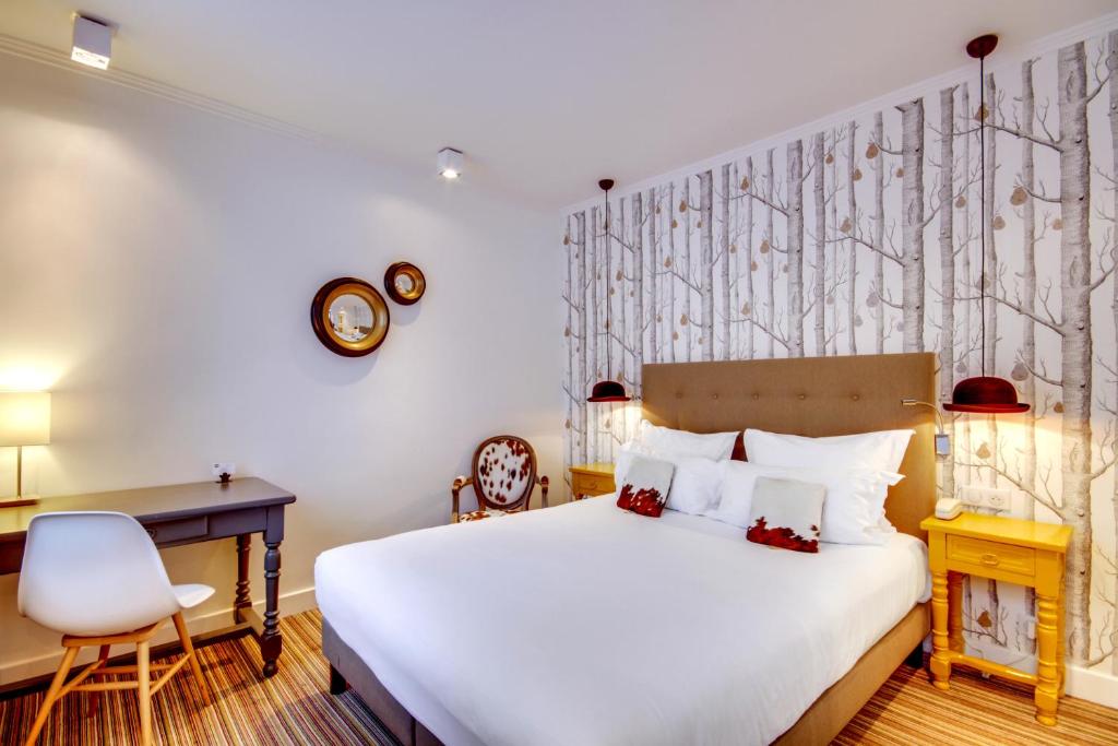 a bedroom with a bed and a desk and a chair at Hôtel Sèvres Saint Germain in Paris
