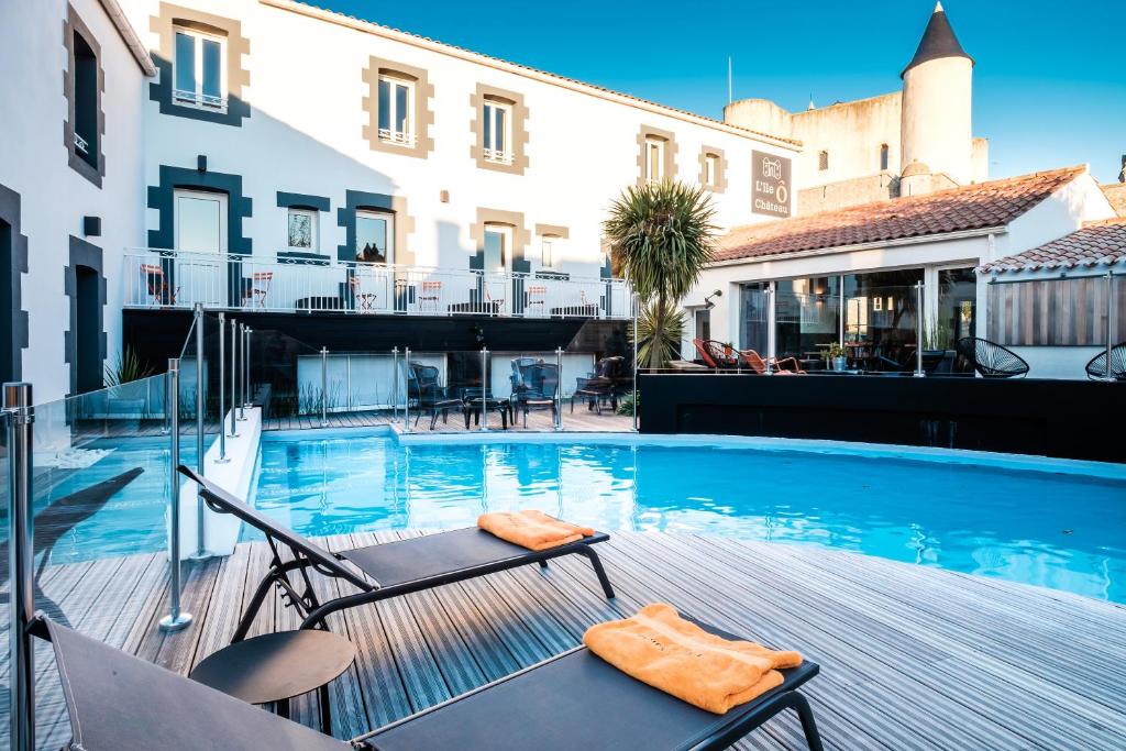 a swimming pool with chairs next to a building at L'Île Ô Château in Noirmoutier-en-l'lle