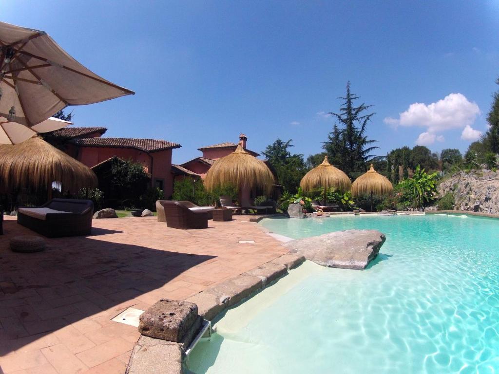 a swimming pool with umbrellas in a resort at Antica Pietrara B&B in Formello