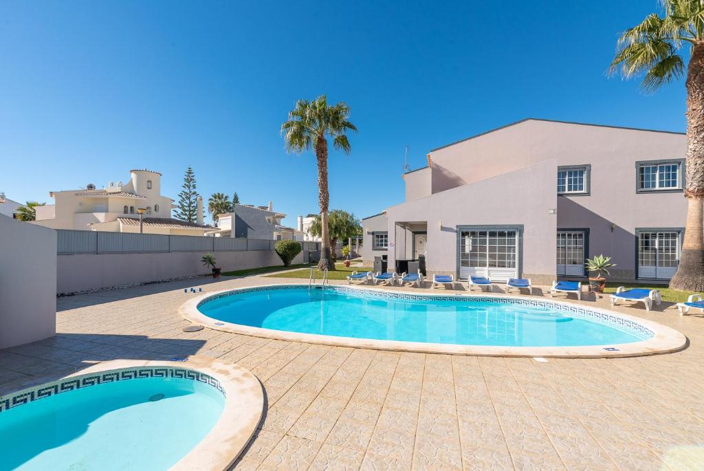 a swimming pool in front of a house with palm trees at Villa Rato by Gabi Miguel in Albufeira