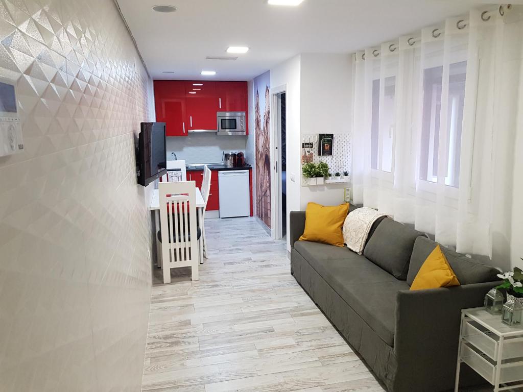 a living room with a couch and a kitchen at Apartamentos Sueños de Toledo in Toledo