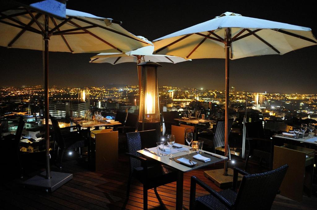 a restaurant with tables and umbrellas on a roof at Hotel Dom Henrique - Downtown in Porto
