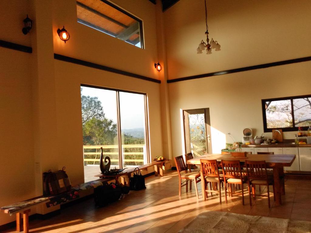 une salle à manger avec une table, des chaises et une grande fenêtre dans l'établissement Jeff Maker TW Workshop, à Emei