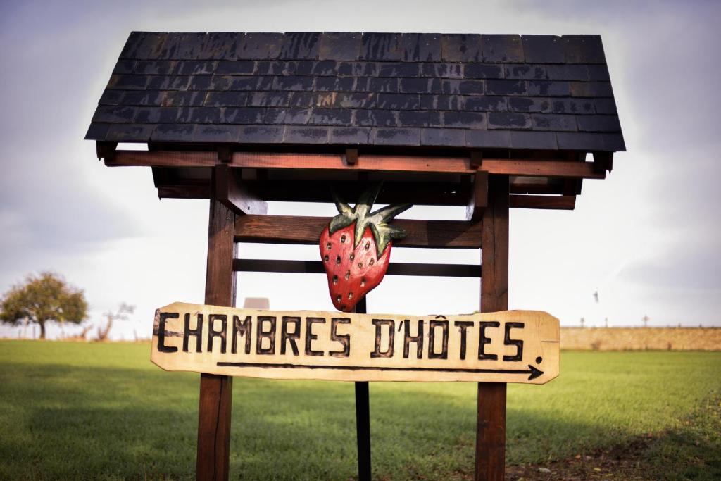 ein Schild mit einer Erdbeere, die aus einem Haus ragt in der Unterkunft Chambres d'Hôtes La Fraiseraie in Tellancourt