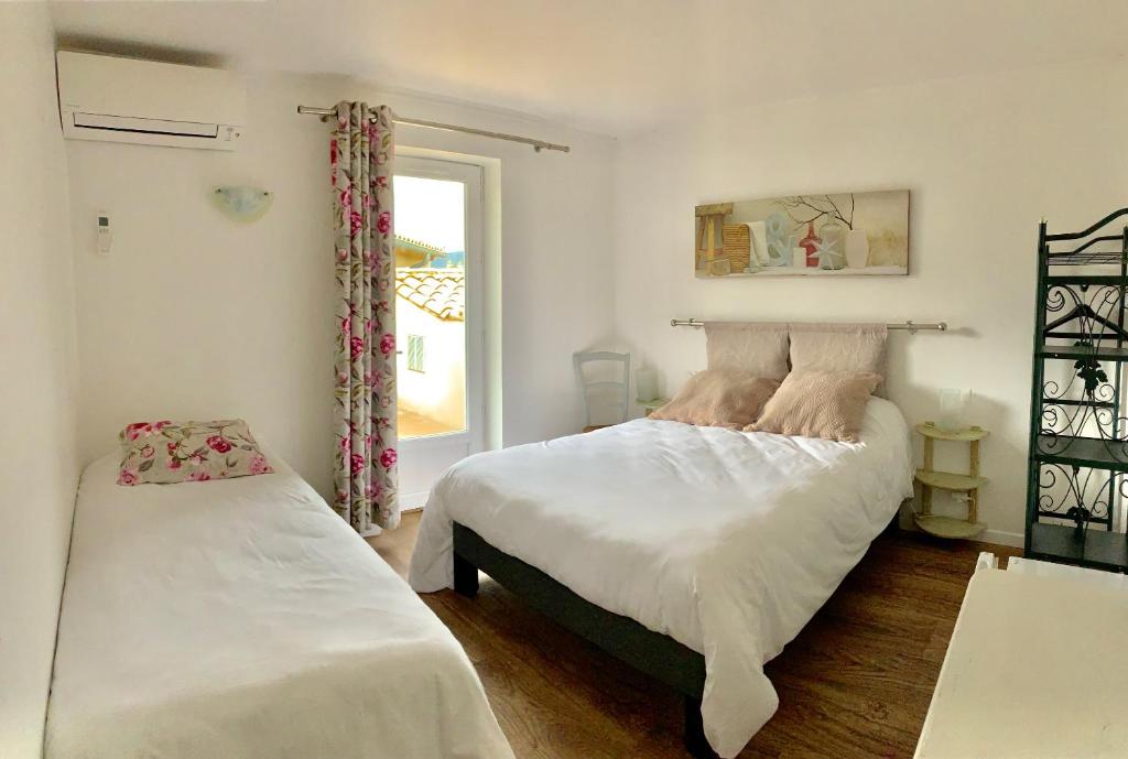 1 dormitorio con 2 camas y ventana en Logis Auberge Cigaloise en Saint-Hippolyte-du-Fort