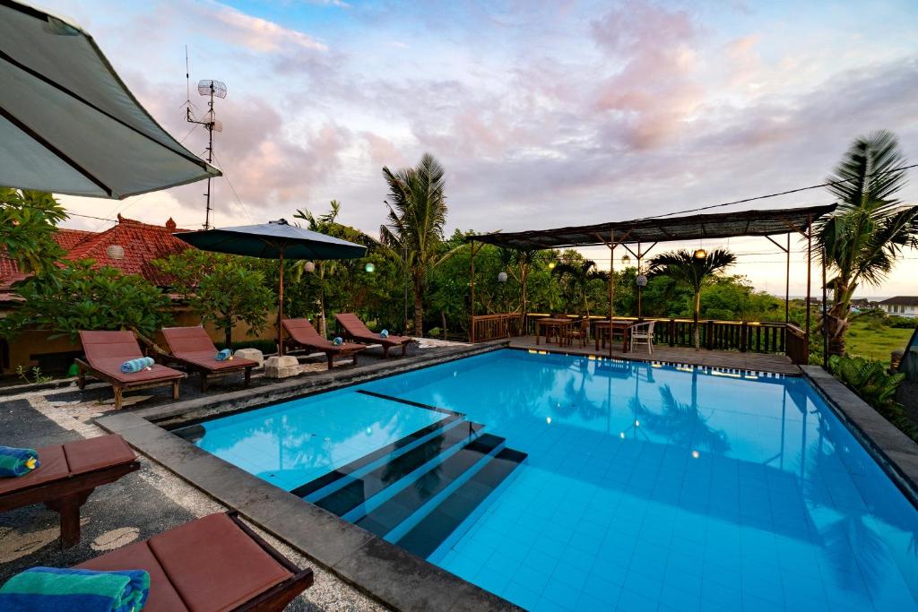 a large swimming pool with chairs and an umbrella at Sedok Jineng Villa in Nusa Lembongan