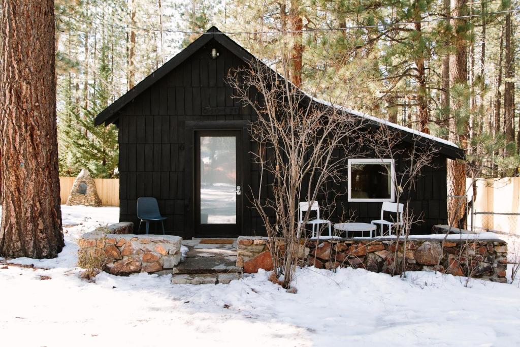 a black cabin in the woods in the snow at Colorado Lodge in Big Bear Lake