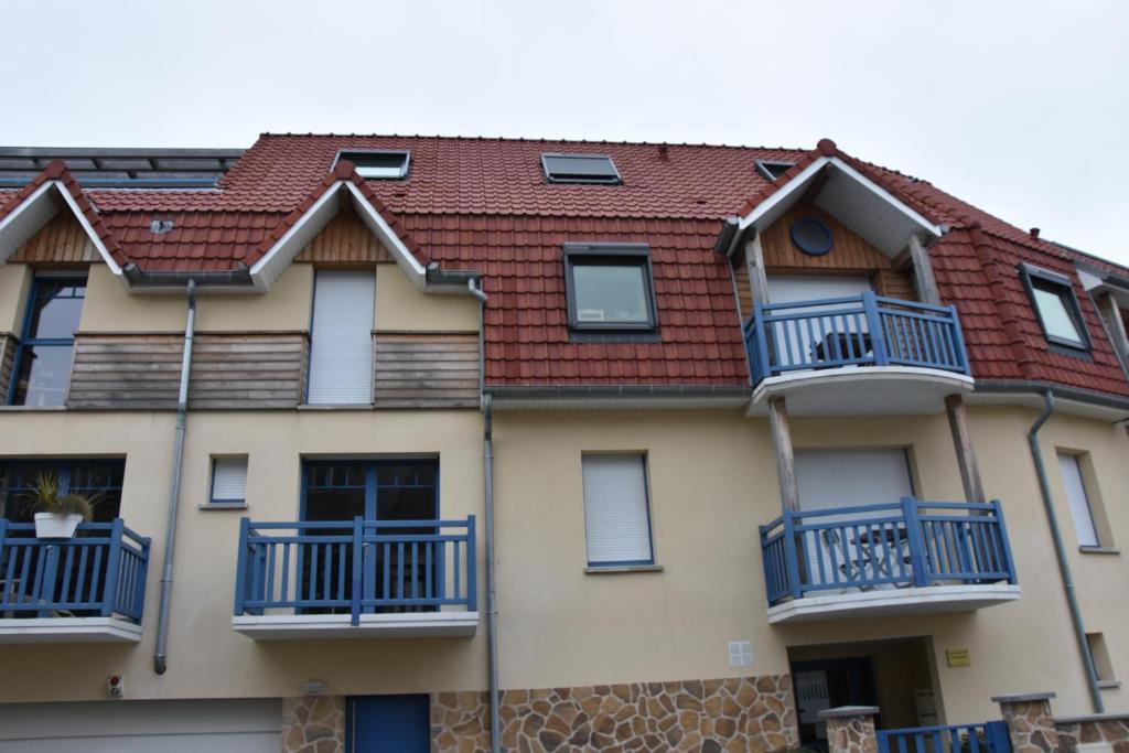 ヴィムルーにあるGîte Le Welcomeの青いバルコニーと赤い屋根の家