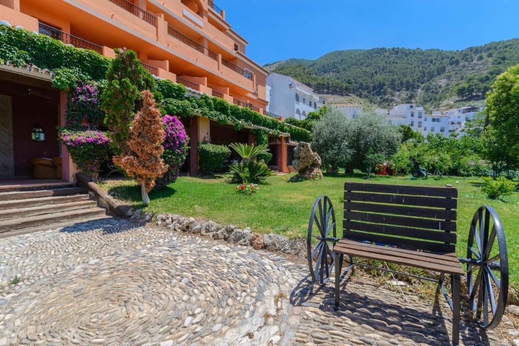 um banco de madeira sentado em frente a um edifício em Apartamentos Sierra Tejeda em Alcaucín