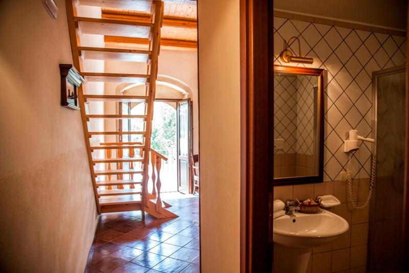 a bathroom with a staircase and a sink and a mirror at Feudo Bauly in Palazzolo Acreide