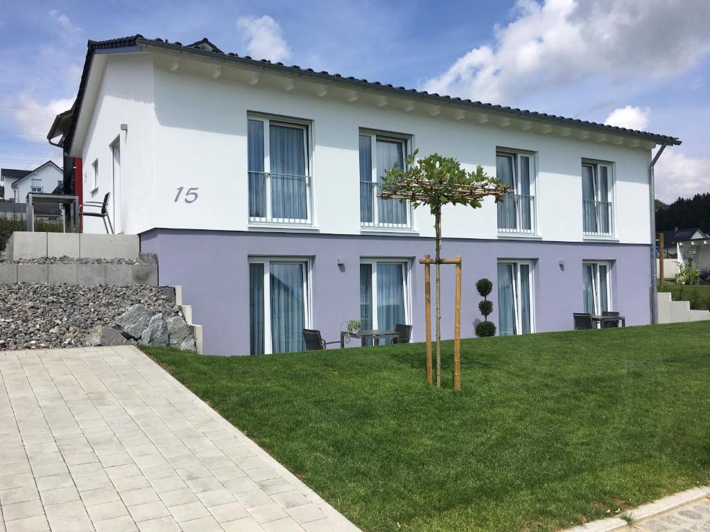 una casa blanca con un árbol en el patio en rent-my-apartment, en Rietheim-Weilheim