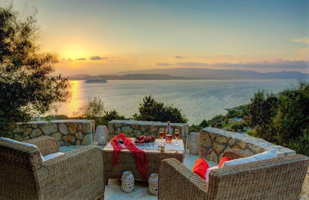 um pátio com uma mesa e cadeiras com vista para o oceano em Ionian Vista Villas em Argostoli