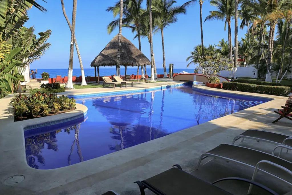a pool at a resort with palm trees and the ocean at Villas Robalo / Dorado Penthouses in Sayulita