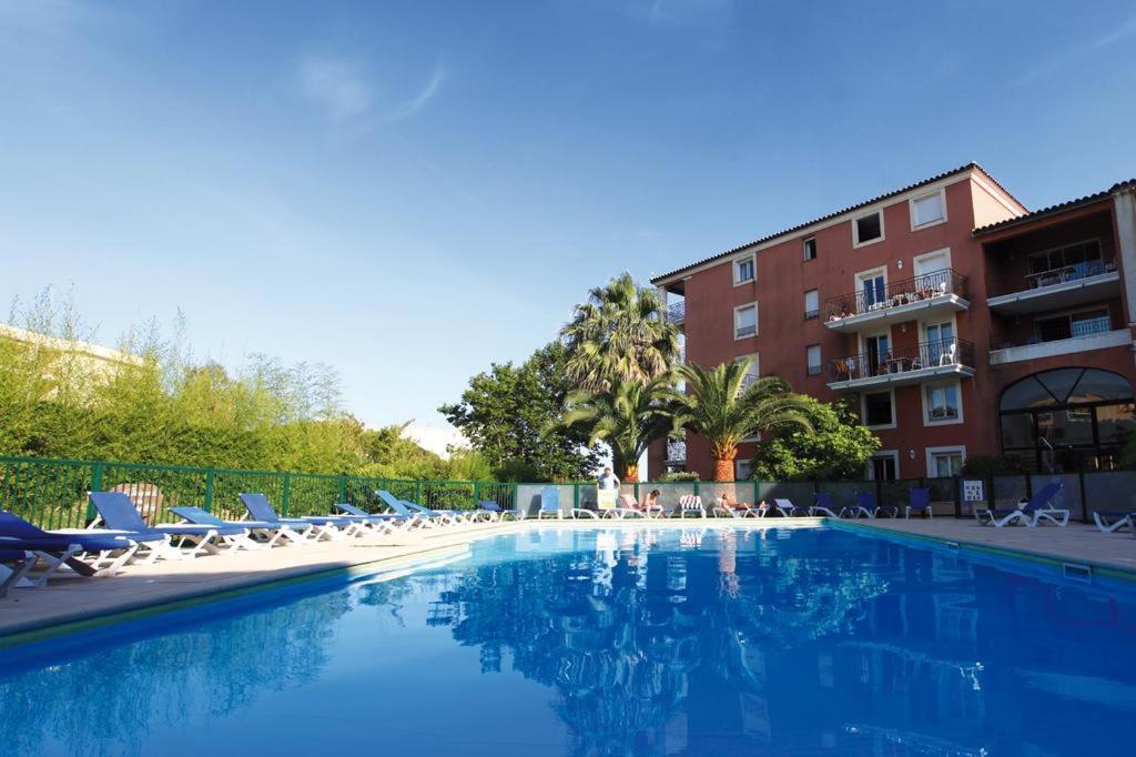 une piscine avec des chaises longues et un hôtel dans l'établissement Résidence 4 etoiles Port Marine, à Sainte-Maxime
