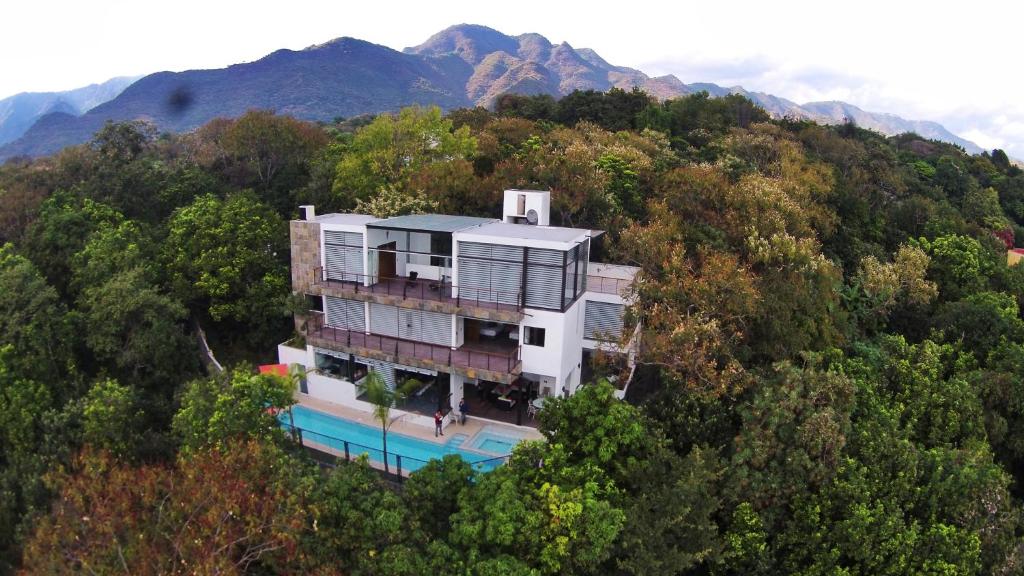 a house in the middle of a hill with trees at Casa de las Aves - Alberca y Jacuzzi climatizados - Espectaculares vistas in Malinalco