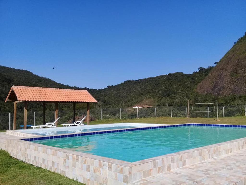uma piscina com duas cadeiras e um gazebo em Chalé duplex reformado - Fazenda Cantinho em Teresópolis