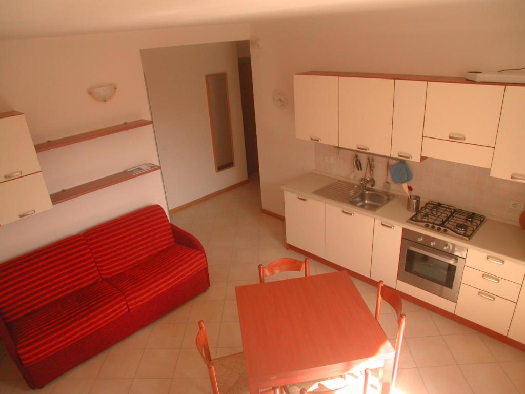 un soggiorno con divano rosso e una cucina di "Il Terrazzo" Apartment a Colico