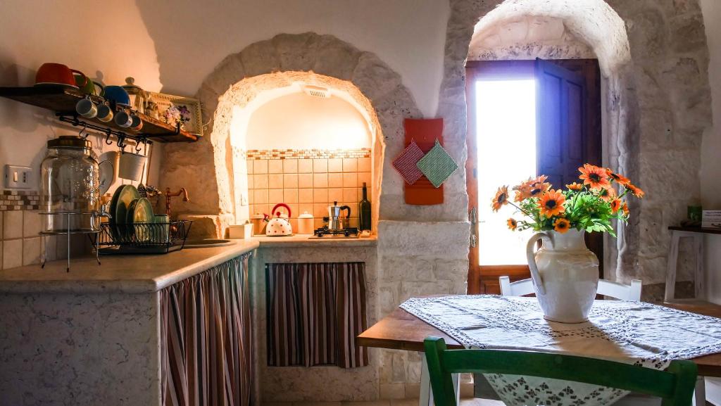 una cocina con una mesa con un jarrón de flores. en Trulli Barsento, en Alberobello
