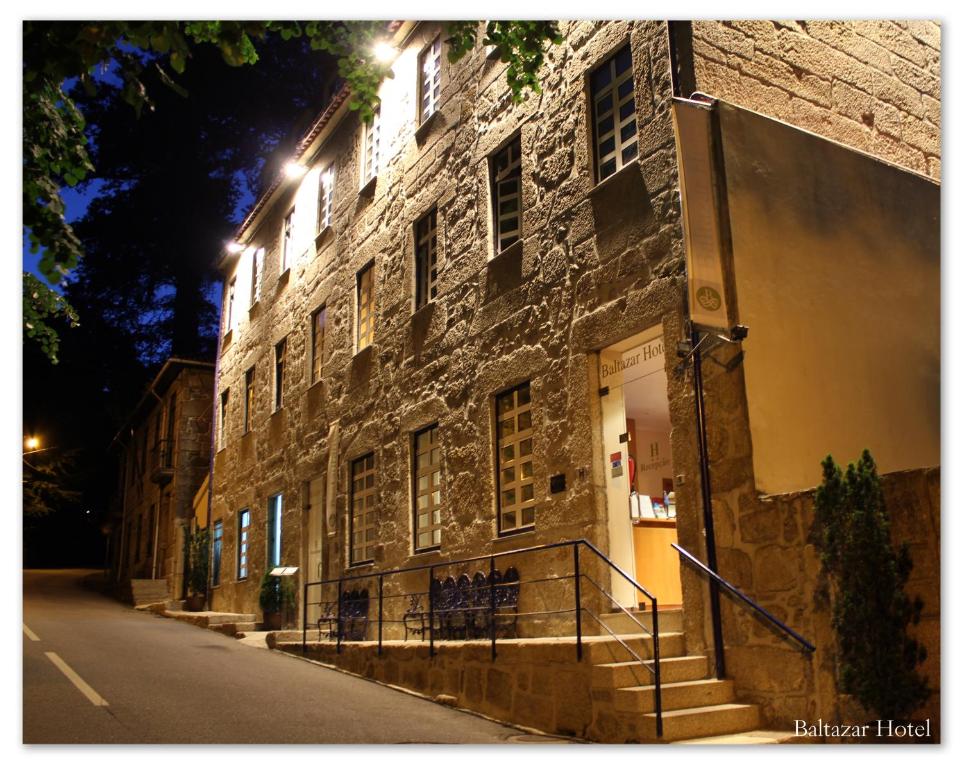 un edificio de ladrillo con escaleras junto a una calle por la noche en Baltazar Hotel, en Gerês