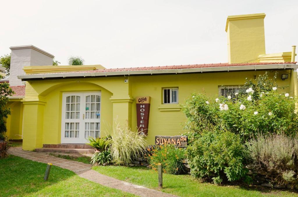 een geel huis met een bord in de voortuin bij Hosteria Suyana in San Salvador de Jujuy