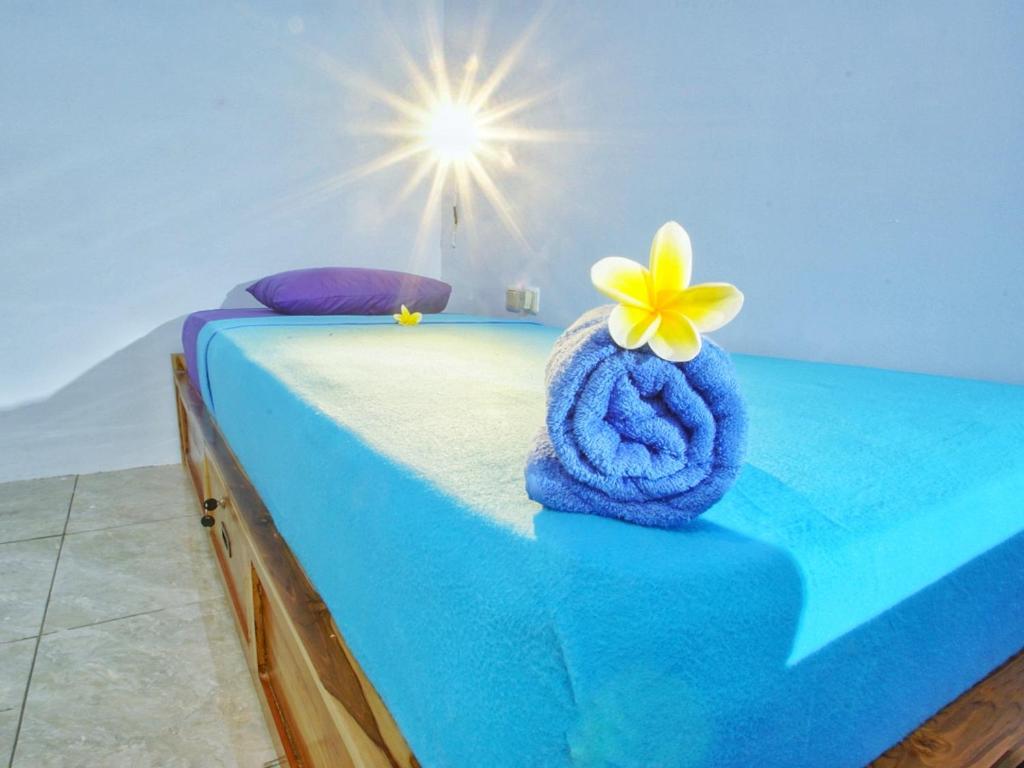 a bedroom with a blue bed with a towel and a flower on it at Sentul Hostel in Kuta Lombok