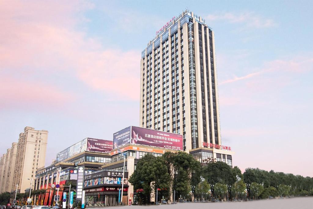 a tall building with trees in front of it at Ramada Plaza Wyndham Wenzhou Cangnan in Wenzhou