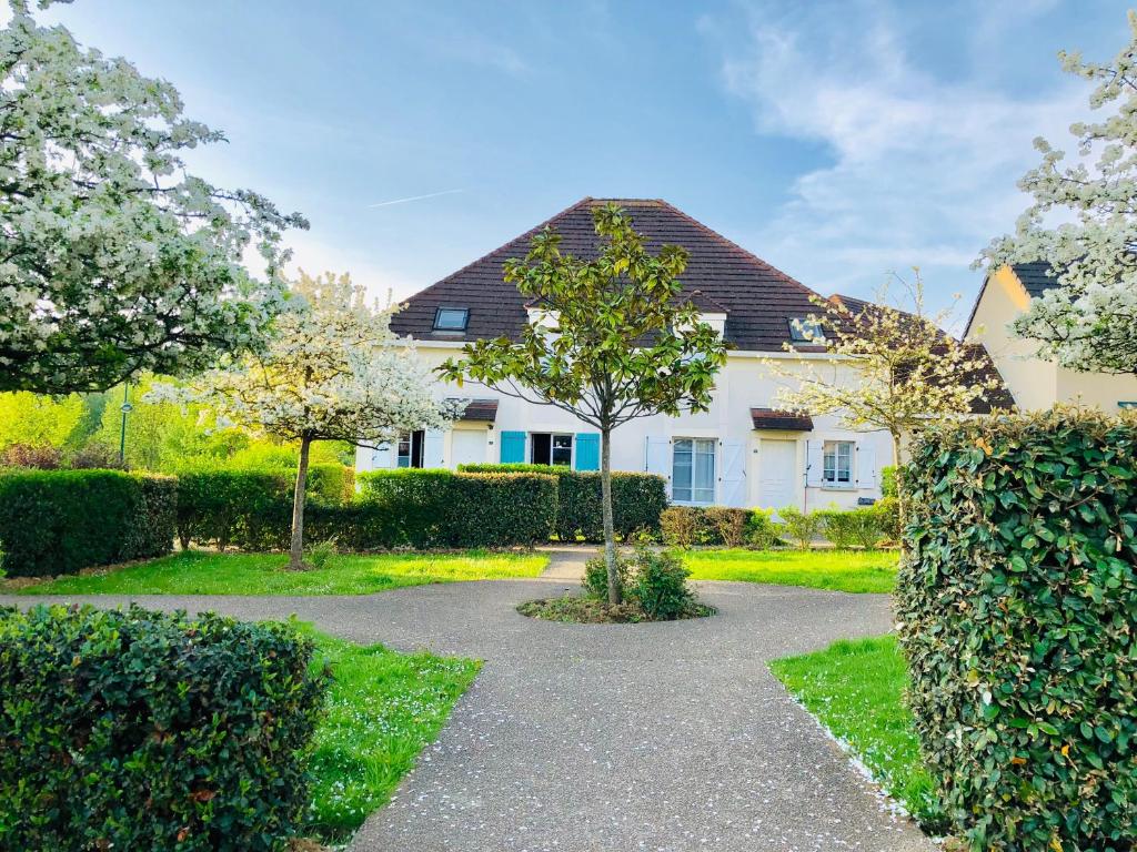 a white house with a tree in the yard at Chambres d'hôtes à thèmes à 2,4Km du parc in Magny-le-Hongre