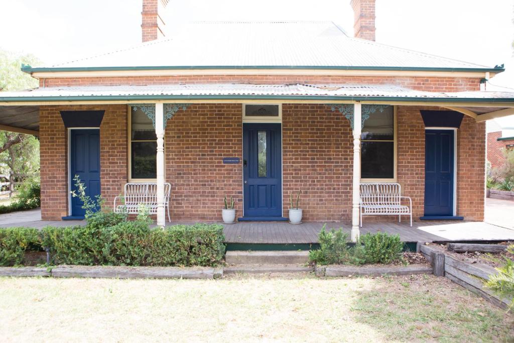 a brick house with a blue door and two chairs at The Bower Mudgee in Mudgee