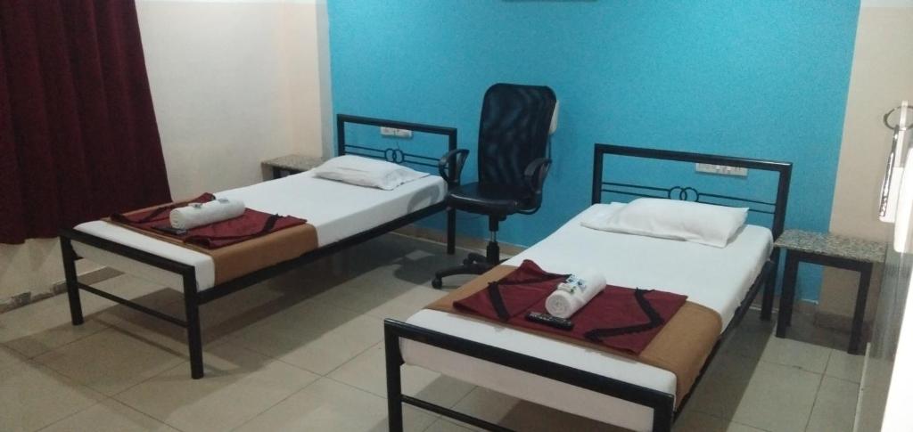 two twin beds in a room with a chair at Deccan Comforts in Hyderabad