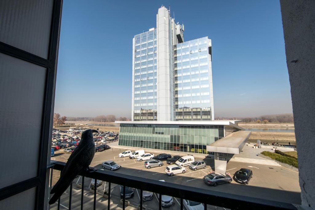 un pájaro sentado en un balcón mirando a un estacionamiento en Delux apartment Moj Osijek, SELF CHECK-IN en Osijek