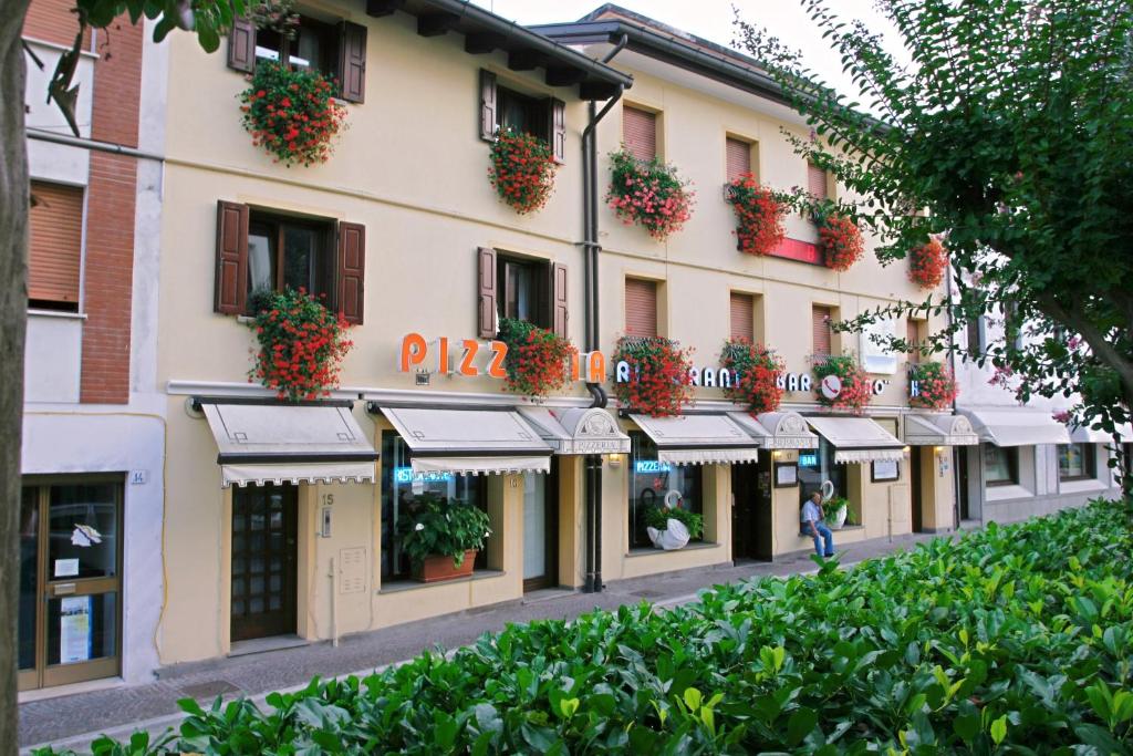 ein Gebäude mit Blumen auf den Balkonen und einer Straße in der Unterkunft Hotel Ristorante Cigno in Latisana