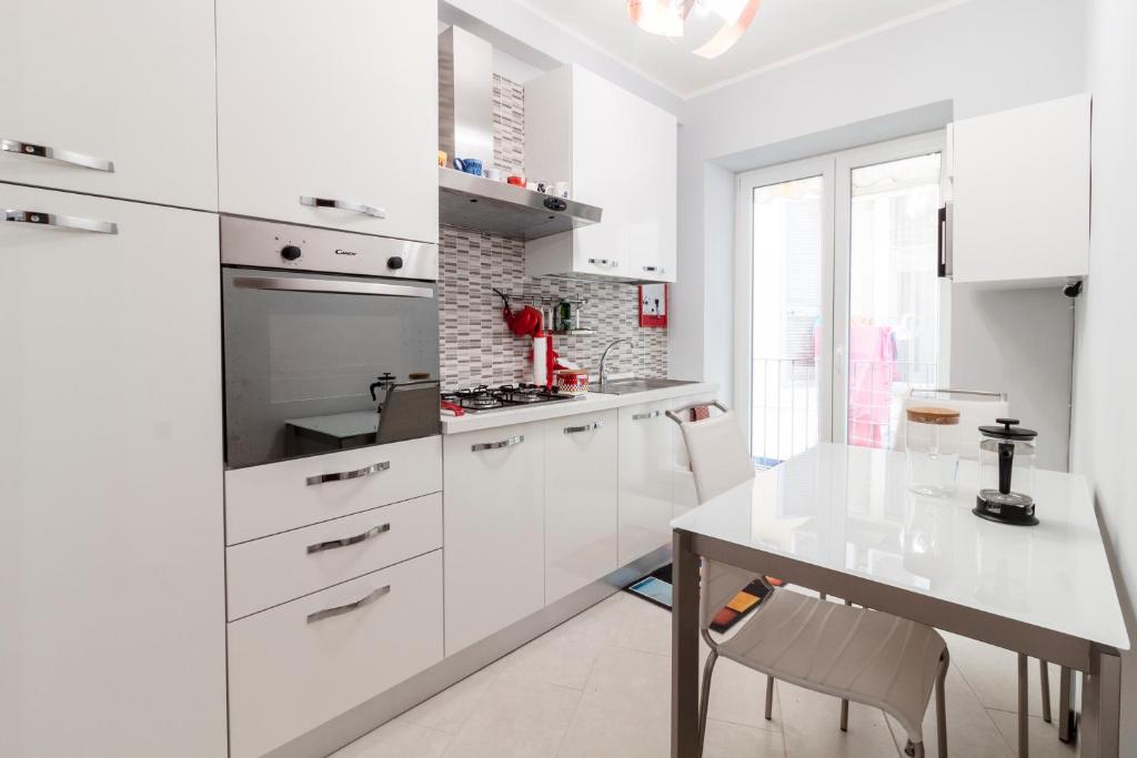 a white kitchen with white cabinets and a table at Casa Gabry in Pozzuoli