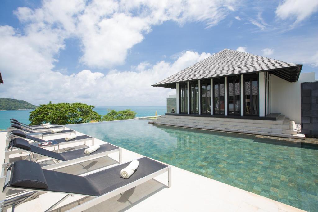 a pool with lounge chairs next to a building at Villa Princess Stephanie in Kata Beach
