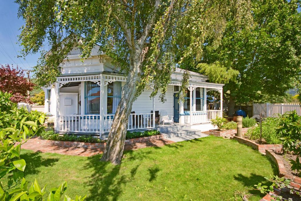 una casa blanca con un árbol en el patio en Grove Garden Villa, en Nelson