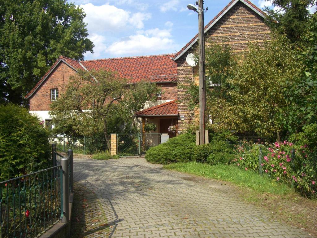 a brick house with a fence next to a driveway at Ferienwohnung Helbig in Tätzschwitz