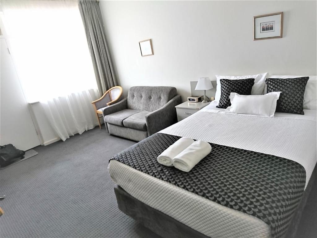 格莱内尔格Glenelg beach gateway Studio Apartment的配有一张大床和一把椅子的酒店房间