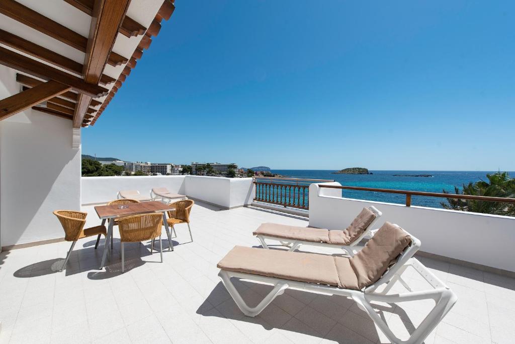 a patio with chairs and a table and the ocean at Apartamentos Es Cañe in Es Cana