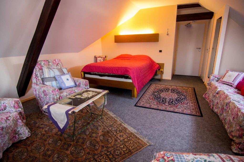 a room with a bed and two chairs and a table at Hôtel de Bâle in Bantzenheim