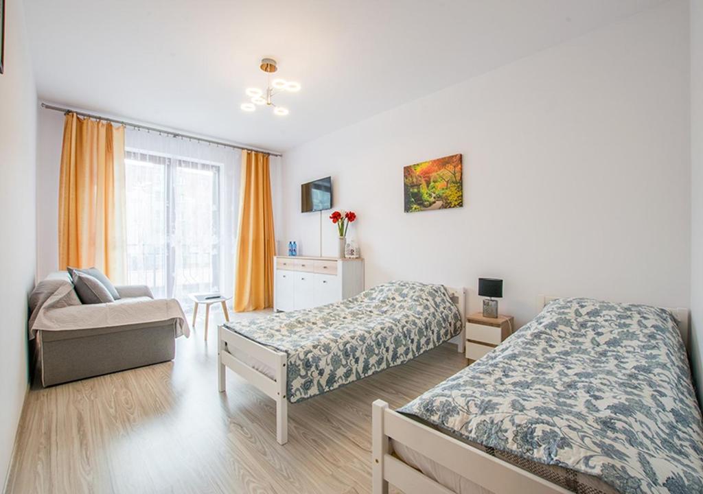 a bedroom with two beds and a chair and a window at Central Apartments Goleniow in Gollnow