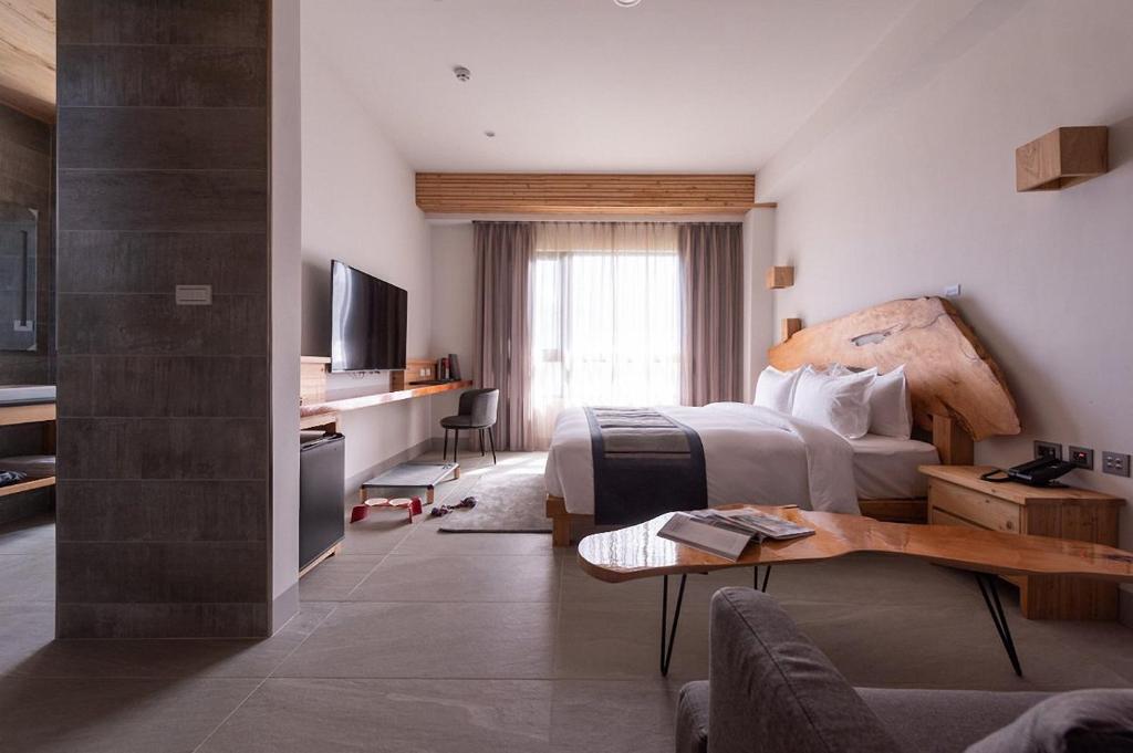 a hotel room with a bedroom with a bed and a table at SkyeBay Club in Hengchun