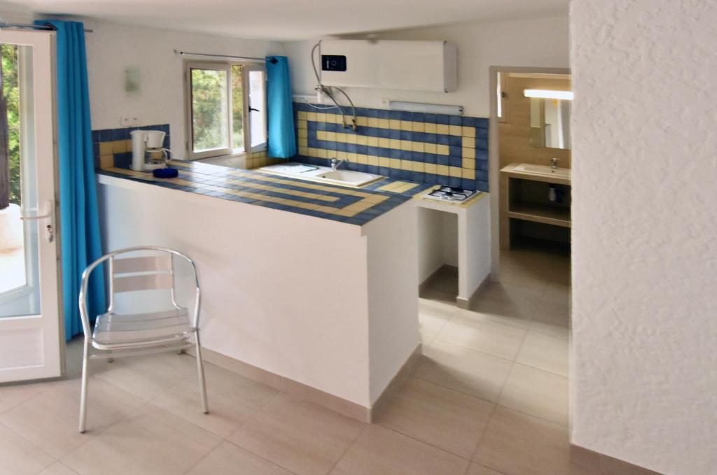 a kitchen with a counter with a chair in it at Village Naturiste La Chiappa in Porto-Vecchio