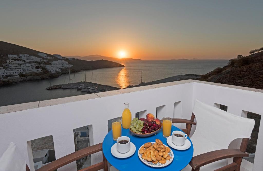 a table with a bowl of fruit on a balcony with the sunset at Yalos rooms in Astypalaia Town