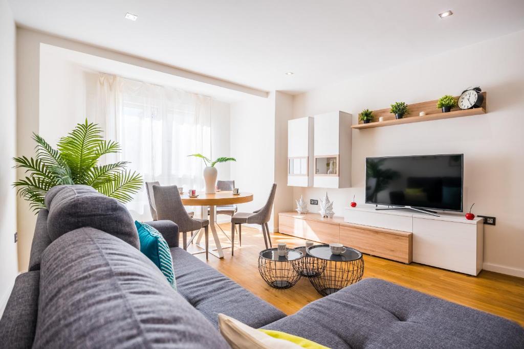 Expoholidays-Rueda Lopez apartamento de lujo في ألميريا: غرفة معيشة مع أريكة وتلفزيون