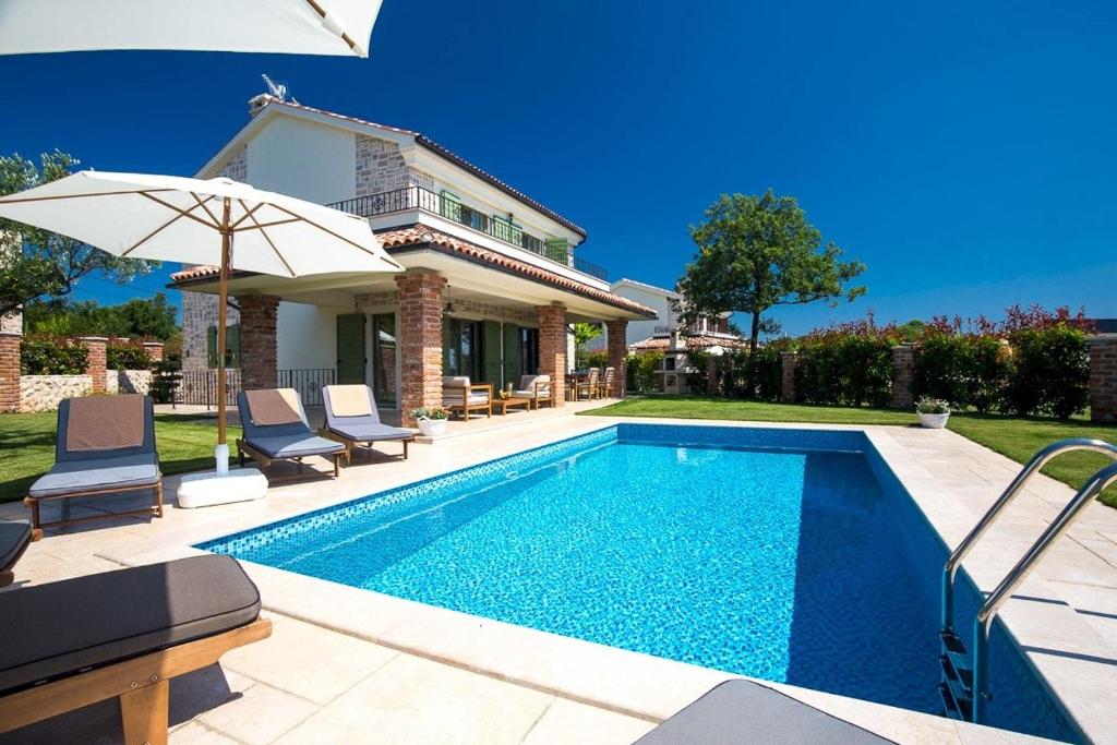 Dobrinj的住宿－Luxury Villa Nika，房屋旁的游泳池配有椅子和遮阳伞