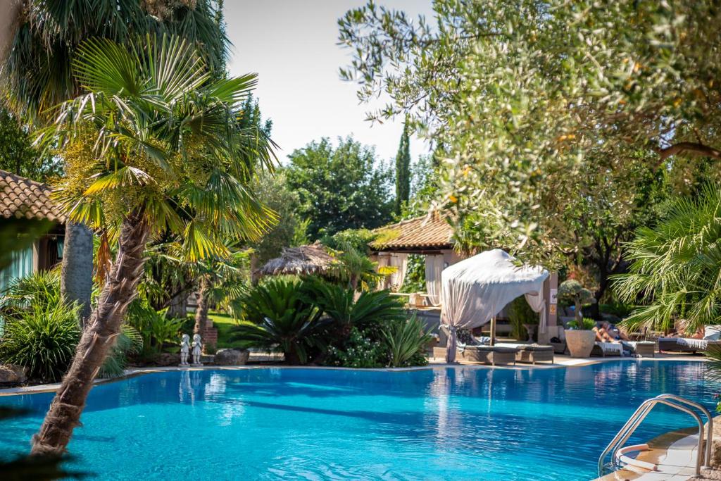 a swimming pool with a palm tree next to a house at Achtis Hotel in Afitos